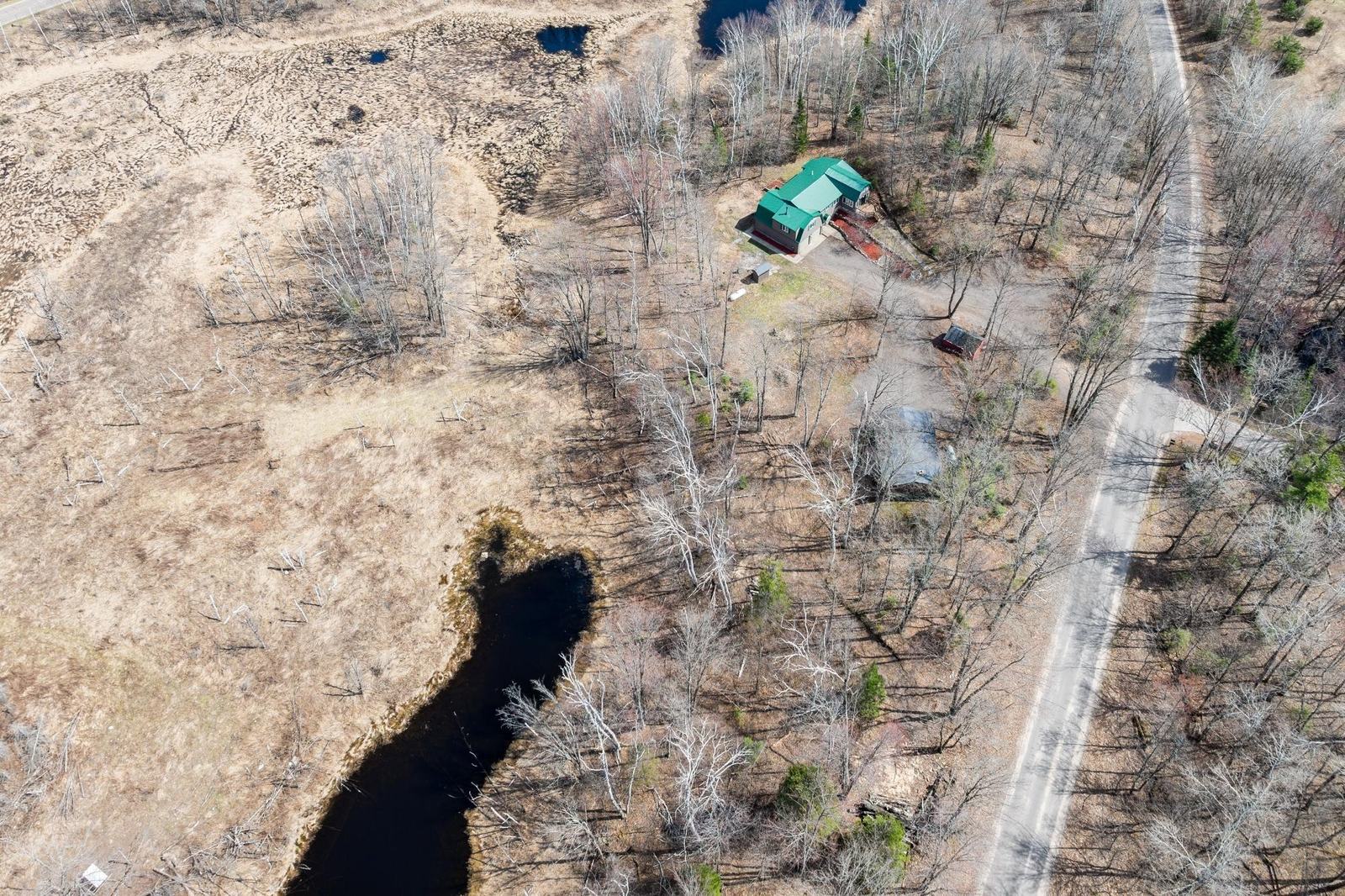 Aerial view of the wooded property with a dark creek winding through bare trees
