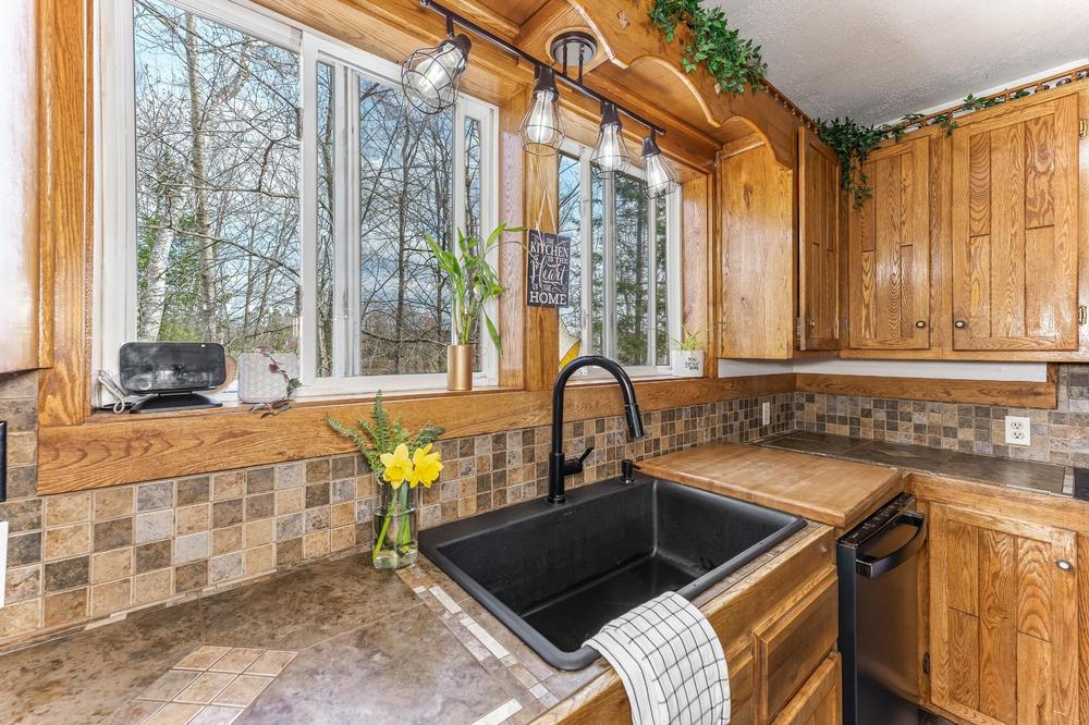 Kitchen sink detail with black fixtures, tile backsplash, and daffodils in a glass jar