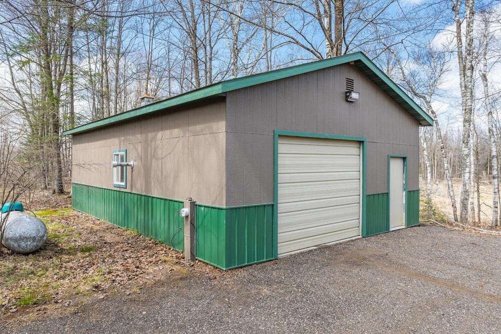 Clear daylight view of the workshop exterior showing the garage door and side entrance